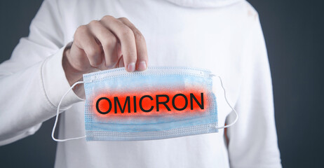 Man showing Omicron text on medical mask.