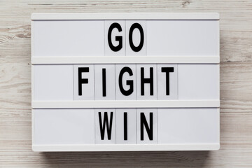 Lightbox with 'Go Fight Win' words on a white wooden background, top view. Overhead, from above....
