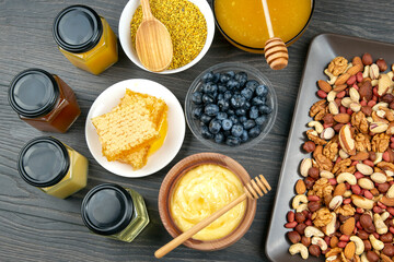 fresh assorted honey, nuts, strawberries and blueberries on a wooden background. healthy organic vitamin food.