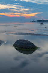 Blue hour after the sunset over rocky Baltic sea cost. Small stones and big boulders in the sea. Long exposure