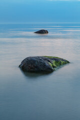 Blue hour after the sunset over rocky Baltic sea cost. Small stones and big boulders in the sea. Long exposure