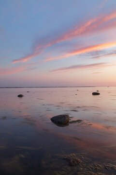 Sunset with a beutiful pink colored clouds. Long exposure photo of rocky sea shore in the evening