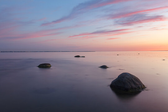 Sunset with a beutiful pink colored clouds. Long exposure photo of rocky sea shore in the evening