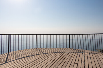 Obraz premium Beautiful wooden terrace with a metal fence is on the beach by the blue sea