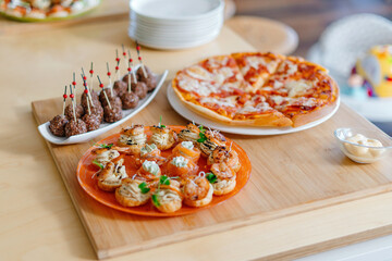 In the foreground salmon with cheese, and stuffed profiteroles. Balls of cream cheese. In the background pizza.