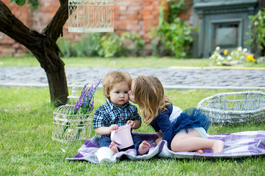 Children on pirnic. Cute kids love. Little girl kissing little boy outdoors in park. Cute little baby on the meadow field. Toddler child walking outdoor, family vacations, summer season nature.