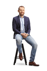 Full length portrait of a man in a suit and jeans sitting on a bar chair