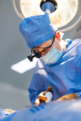 Neurosurgeon in operation room. Attentive doctor in surgical glasses provides operation. Selective...