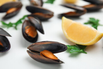 Cooked mussels with parsley and lemon on white table, closeup