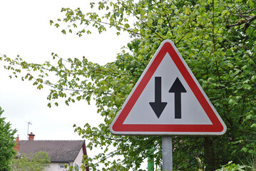 Triangular Road Sign with Direction Arrows on Metal Pole in Close Up 