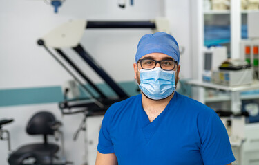 Fototapeta na wymiar Portrait of surgeon wearing surgical gloves and scrubs in operation theater. Doctor in scrubs and medical mask in hospital operating room.