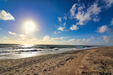 Panoramic view of Baltic sea from sandy shore, sand dunes. Dramatic sky with glowing clouds, sunbeams. Denmark