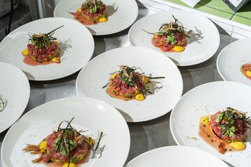 Tartarus from young calf with avocado, garnished with nori leaves and parsley. Many plates are ready to be served to the guests.