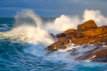 Ocean waves splashing on the big red rocks