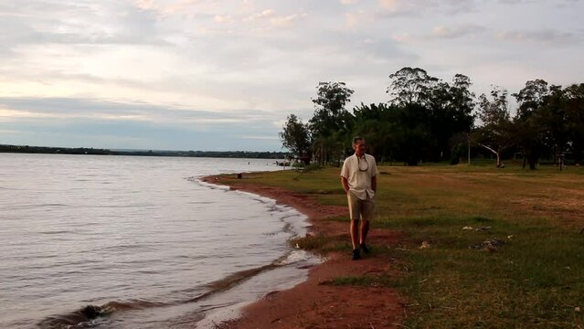 Mature Man walking along Lago Paranoa at Parque das Garcas in Lago Norte Brasilia, Brazil