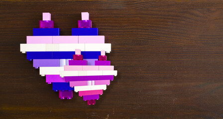 Obraz premium Bricks in the shape of a heart on a wooden background with copy space. Conceptual photo for valentine's day