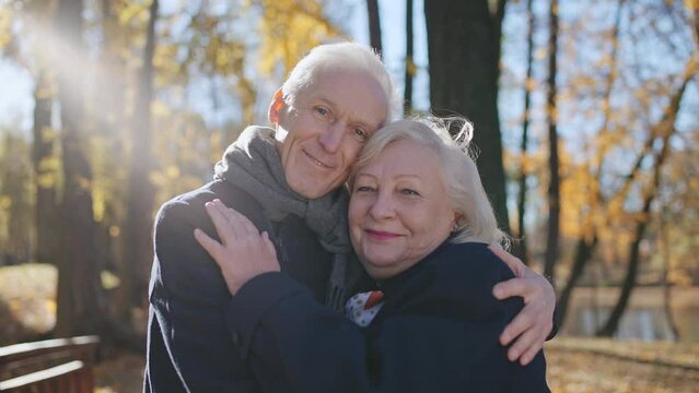 Portrait of senior couple hugging and smiling in park, happy retirement together
