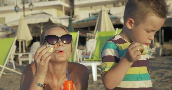Mother and child blowing bubbles on the beach