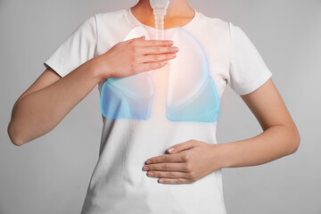 Woman holding hands near chest with illustration of lungs on light grey background, closeup