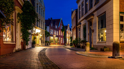 Fototapeta na wymiar illuminated alley in the old town of Leer in the blue hour