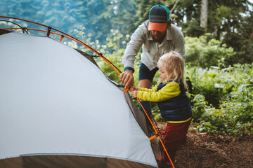 Child and father are pitching camping tent family travel vacations hiking outdoor adventure trip healthy lifestyle eco tourism - obrazy, fototapety, plakaty