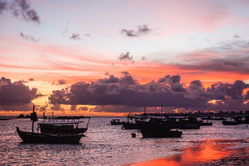 Silhouette Of Boats Moored In The Tropical Beach At colored Sunset.