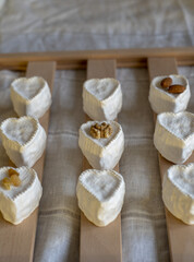 Fototapeta na wymiar A lot of small cheeses in the shape of a heart, covered with white mold, on a wooden stand. Home production from natural products.