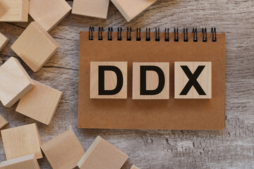 DDX Differential diagnosis 3 three wooden blocks on notepad, top view on wooden background