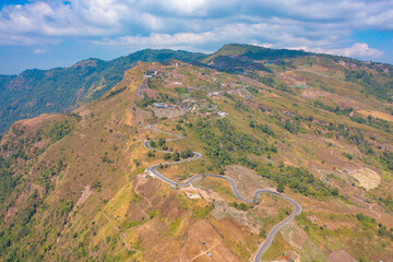 Fototapeta na wymiar Aerial view of cars driving on curved, zigzag curve road or street on mountain hill with green natural forest trees in rural area of Nan, Thailand. Transportation.