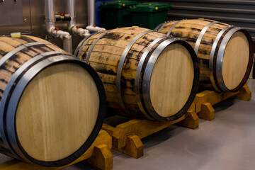 Wooden beer or wine barrels with iron rings in the cellar. Modern Factory. Brewery. Rows of wine barrels in an aging cellar