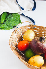 Straw basket with vegetables on white background. Flat lay, top view, copy space.