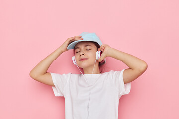 Portrait of happy smiling child girl headphones in a white t-shirt and a cap Lifestyle unaltered