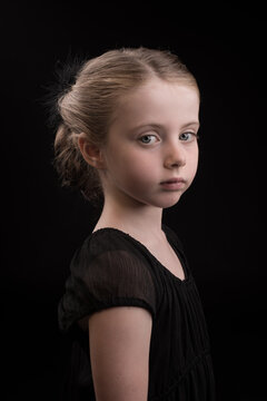 Classic painterly dark studio portrait of a young girl in black