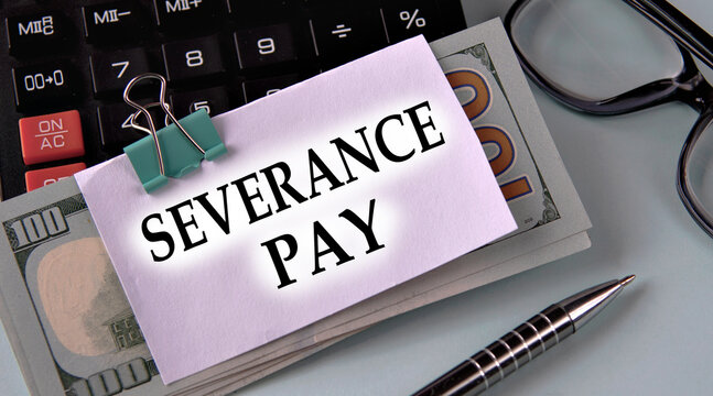 SEVERANCE PAY - words on a white piece of paper fixed on banknotes against the background of a calculator, glasses and pen