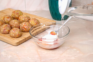 A man pours hot water into a sauce to cook lazy cabbage rolls in a slow cooker.