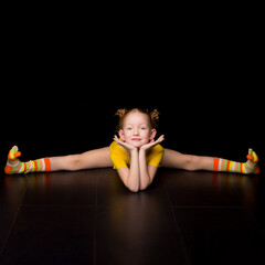 Cute happy young girl gymnast doing cross splits