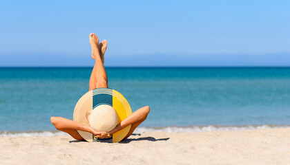 A slender girl on the beach in a straw hat in the colors of the Canaries flag. The concept of a perfect vacation in a resort in the Canary Islands. Focus on the hat.