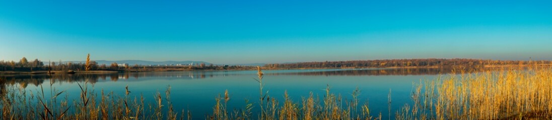 Naklejka na ściany i meble Panoramic view of a calm lake on a sunny summer day