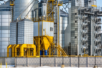 agro silos granary elevator in winter day in snowy field. Silos on agro-processing manufacturing plant for processing drying cleaning and storage of agricultural products, flour, cereals and grain.