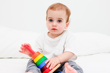 Pretty child 1 years old wearing white tshirt playing with wooden pyramid. Concept of wooden toy, children development