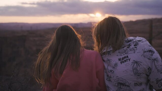 Smiling two young women friends having fun on the sunset beach, queer non-binary gender identity, gay lesbian love romance, boho summer vacation style wearing jeans