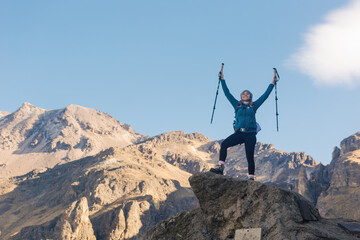 Woman hiker portrait. She is standing on a mountain peak, looking at nature landscape