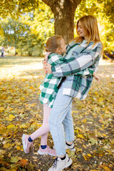 Mom and baby together. Young mother hugging and kissing her little son in autumn park. Happy family