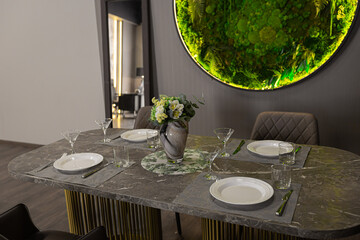 stylish luxurious dining room interior in an ultra-modern apartment in dark colors with a very cool green moss decorative panel on the wall with led lighting
