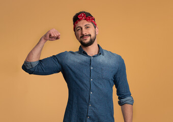 Portrait of a man, a supporter of the feminist movement, wearing a denim shirt, and a white polka dot bandana. Orange background.