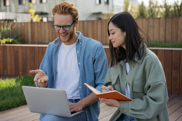 Smiling multiracial students studying, distance learning, education concept	Team of young colleagues using laptop computer, communication, taking notes working online outdoors