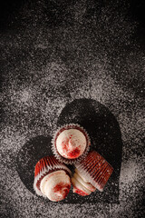 Red Velvet Valentine's Day cupcakes with powdered sugar heart shape on black background.