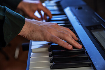 Male hands playing electric Digital Piano. Musician man with black guitar at a rock concert