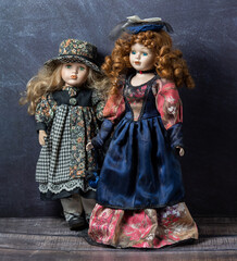 Amazing realistic vintage toys with green and blue eyes.The dolls dressed in a beautiful dresses and have a blond-red hair. Selective focus. Porcelain dolls.