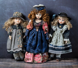Amazing realistic vintage 3 toys with blue and green eyes.The dolls dressed in a beautiful colored dresses. Selective focus. Porcelain dolls.